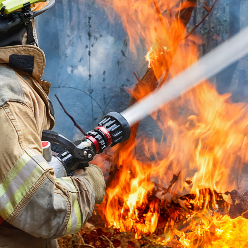 Firefighter spraying water on fire